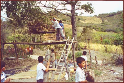 men threshing millet by hand, with children in foreground